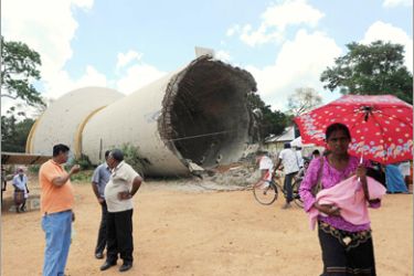 AFP- In this picture taken on April 29, 2010, Sri Lankans walk past a fallen water tower that was blown up by Tamil Tiger rebels in the 1990s in the northern