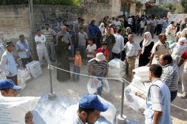 Palestinians wait to receive food aid donated for refugees from the European Union and the World Food Programme (WFP) and distributed by the United Nations Relief