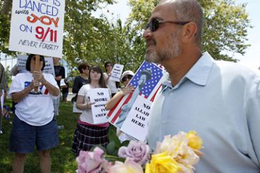 r_Terek Ayoub brings flowers to protesters across the street from his temporary mosque, at a business warehouse where the Islamic Center of Temecula Valley currently hold their