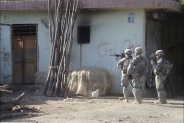 f_International Security Assistance Force (ISAF) soldiers stand alert beside a building in Kunduz on July 2, 2010, after a suspected militant attack in the northern Afghan city