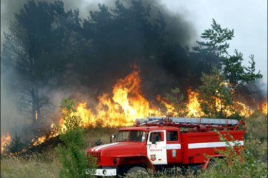 r : A fire truck parks near burning grass and trees, outside the town of Novovoronezh, some 40 km (25 miles) south of the city of Voronezh, August 2, 2010. Russia's leaders