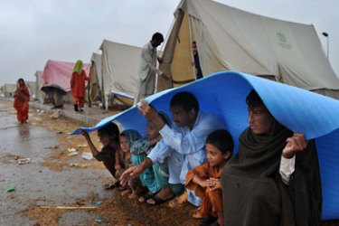 : Pakistani flood survivors shelter from a rain shower on a roadside in Nowshera on August 7, 2010. Pakistan raced to evacuate families threatened with fresh floods, as heavy rains worsened the disaster in its second week, with up to 15 million people already affected