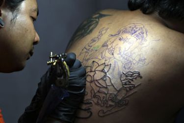 A Nepalese tattoo artist inks a customer's back with a depiction of the Hindu deity Ganesha in Kathmandu on August 7, 2010