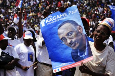 r : A supporter of the ruling Rwandan Patriotic Front holds a poster of incumbent President Paul Kagame at a rally ahead of next week's presidential election, in Byumba August 2,