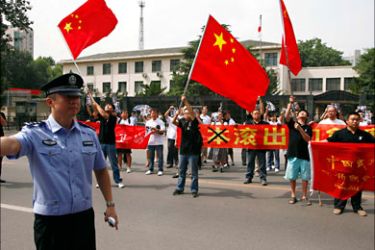 r_A policeman pushes back members of the media as a group of protesters carrying banners and waving Chinese flags arrive outside the Japanese embassy in Beijing September 8, 2010