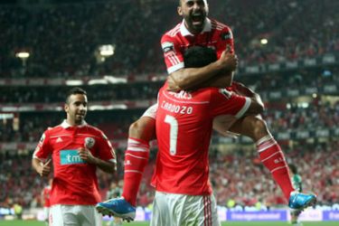 Benfica's Paraguayan striker Oscar Cardozo (2ndL down) is mobbed by teammate Carlos Martins after scoring against Sporting during their Portuguese League football match at Luz Stadium in Lisbon on September 19, 2010.