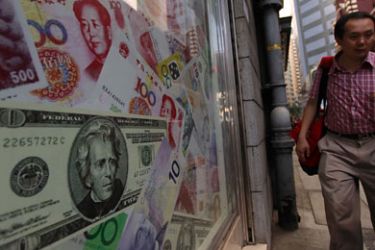 epa02333459 A man walks past oversize Chinese yuan (RMB) notes, US bank notes and other foreign currency are seen out side a foreign exchange in Hong Kong, China 13 September 2010.