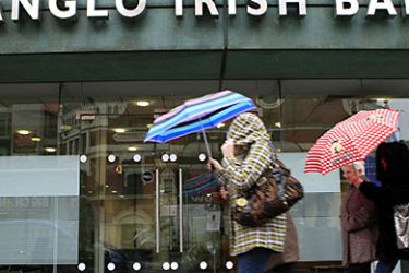 A file photo taken on March 31, 2010, shows people walking past a branch of an Anglo Irish Bank in Belfast, Northern Ireland. Ireland warned on Thursday September 30, 2010, that the state rescue of Anglo Irish Bank could cost 34.3 billion euros, pushing the public deficit up to 32 percent of economic output this year. The potential rescue bill, equivalent to 46.6 billion dollars, is roughly the same as Ireland's annual taxation revenues. AFP