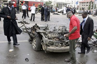 Security agents check a damaged car following a blast in Abuja during the 50th independence anniversary ceremony in Abuja on October 1, 2010. Explosions rocked an area near Nigeria's independence celebrations on Friday and killed at least seven people following threats from oil militants, witnesses and a police source said. AFP