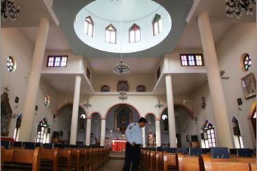 FILES) -- File picture dated December 24, 2008 shows an Iraqi policeman conducting a security check inside a church in Baghdad's Karrada neighbourhood. Gunmen have taken worshippers hostage in a Baghdad church where they fled after shooting dead two guards at the