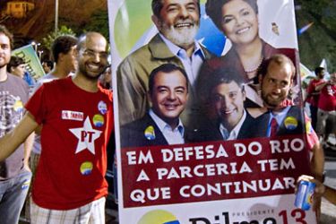A supporter of Brazilian President elect Dilma Rousseff poses with a campaign banner celebrating her victory at Leme beach, in Rio de Janeiro, Brazil on October 31, 2010. Rousseff has become the first female President of Brazil, after early results showed her receiving 56% of votes against 43% received by her rival, candidate for the Brazilian Social Democratic Party (PSDB), Jose Serra.