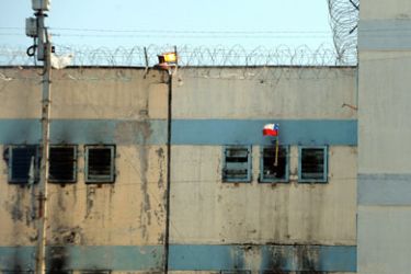 Santiago, Regi&oacute;n Metropolitana de Santiago, CHILE : An inmate waves a Chilean flag from his cell at the San Miguel prison after a fire, in Santiago, December 8, 2010. The fire killed at least 81 inmates in the prison early Wednesday in what officials called the worst ever disaster at a Chilean prison. AFP PHOTO/Claudio SANTANA