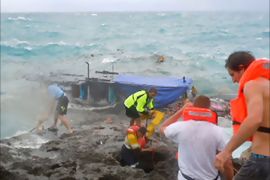 Residents and police (R) try to rescue refugees from an asylum boat (C) being smashed by violent seas against the jagged coastline of Australia's Christmas Island on December 15, 2010.