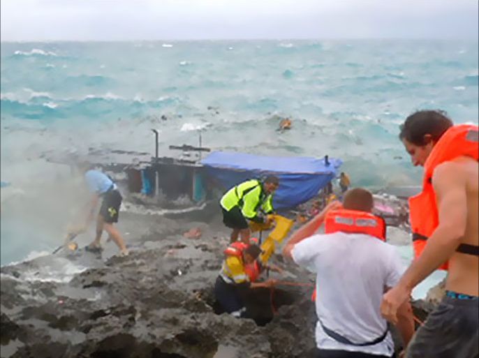 Residents and police (R) try to rescue refugees from an asylum boat (C) being smashed by violent seas against the jagged coastline of Australia's Christmas Island on December 15, 2010.