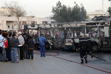 epa02518582 Firefighters inspect the wreckage of a burnt out bus during violent protests against recent price hikes in some food products as flour, sugar and milks in Algiers, Algeria, late 06 January 2011. Riots erupted in Algeria over food prices, housing and lack of work,