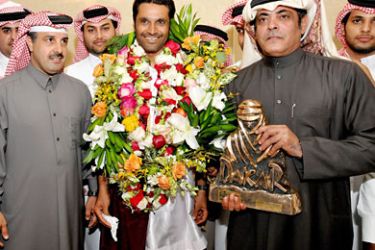 In this handout picture from the Qatar Olympic Committee, Qatari driver Nasser Bin Saleh al-Attiyah (C) poses with his Dakar rally trophy with unidentified officials upon his arrival in Doha, late on January 18, 2011. Attiyah is the first Arab driver to win an international rally. AFP PHOTO