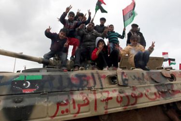 epa Libyan children flash 'Victory' signs and hold Libyan flags from the pre-Gaddafi era as they pose for photographs on top of a military vehicle in Benghazi, eastern Libya, 26 February 2011