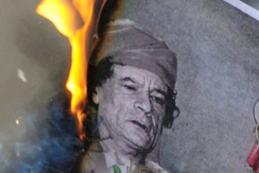 A man burns a picture of Libyan leader Muammar Gaddafi during a demonstration near the Libyan consulate in Paris February 25, 2011. Libya's ambassador to France and another diplomat from Tripoli resigned on Friday in response to the revolt against leader Muammar Gaddafi, a Libyan official said.