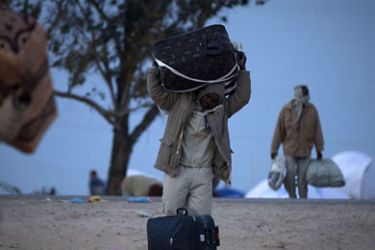 Sudanese refugees who fled Libya carry bags upon arrival at the Choucha refugee camp, near the Tunisian border town of Ras Jdir on March 9, 2011.