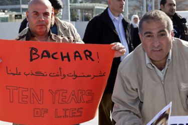 A Syrian protester holds a sign with the message 'Bachar! Ten years of lies' during a protest in support of the anti-government protests in Syria, in the Place des Nations in front of the European headquarters of the United Nations in Geneva