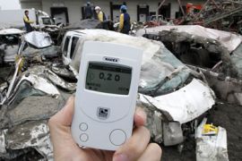 A photographer holds a radiation detector indicating 0.35 microsieverts per hour at a devastated factory area hit by earthquake and tsunami in Sendai, northern Japan, March 20, 2011
