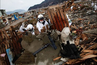 r_Policemen lift a collapsed wall of a house as they search for bodies of tsunami victims more than two weeks after the area was devastated by a magnitude 9.0 earthquake