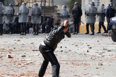 A protester throws a stone towards riot police during a demonstration in Mahsoul near Algiers Mars 16, 2011. Police in the Algerian capital used tear gas on Wednesday to disperse a crowd of young men who were throwing petrol bombs and stones, a Reuters reporter said. The protesters, who had blocked a road in the east of the capital, said they had no political demands but wanted the authorities to give them better housing.
