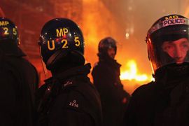 Police officers stand guard in front of a fire near Piccadilly Circus following a mass rally in Hyde Park in protest at government cuts on March 26, 2011 in London, England