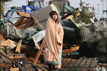 ق_A woman looks at the damage caused by a tsunami and an earthquake in Ishimaki City, Miyagi Prefecture, after the magnitude 8.9 earthquake struck the area March 13, 2011