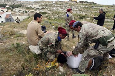 f_A migrant is helped by Italian soldiers after getting injured while escaping with others from a temporary detention center on the Italian island of Lampedusa, on April 11, 2011. Around 26,000