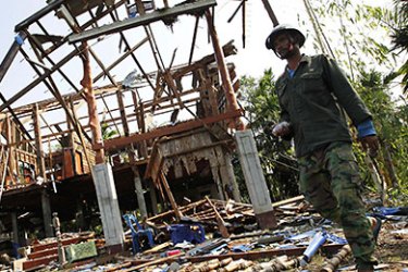 A villager walks near a damaged house in Karb Cherng village in Surin province April 27, 2011, following armed clashes on a disputed border area between Cambodia and Thailand.