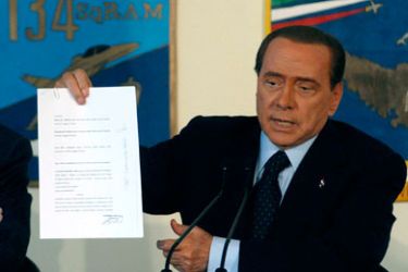 Italian Prime Minister Silvio Berlusconi shows a document during a news conference at the end of a visit at the southern Italian island of Lampedusa April 9, 2011.