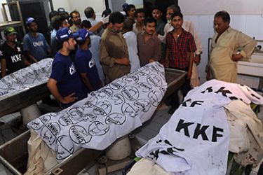 People gather around the bodies of men killed in a bomb blast on April 21, 2011, at a hospital in Karachi. At least 16 people were killed and more than 30 wounded in a blast at a gambling den in Pakistan's southern port city of Karachi late on April 21, senior police