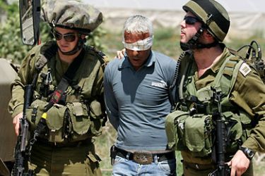 Israeli soldiers detain a Palestinian man who was trying to prevent Israeli bulldozers from demolishing water wells near Palestinian agricultural farms in the village of Kafr Dan near the West Bank city of Jenin
