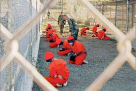 REUTERS/ Detainees sit in a holding area during their processing into the temporary detention facility, as they are watched by military police, at Camp X-Ray inside Naval Base Guantanamo Bay in this January 11, 2002 file photograph. Al Qaeda leader Osama bin Laden was killed in a firefight with U.S. forces in Pakistan on May 1, 2011, ending a nearly 10-