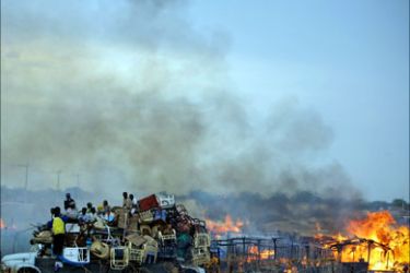 A handout picture released by the United Nations Mission in Sudan (UNMIS) on May 28, 2011, shows a truck piled high with looted items as it drives past businesses and homesteads locally known as 'tukuls' burning in the centre of the disputed Sudanese central town of Abyei