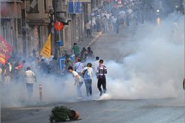Protesters run amidst tear gas smoke during clashes between Kurdish and Turkish leftist groups and riot policemen, on June 22, 2011, in Istanbul. Newly-elected Kurdish lawmakers came under pressure on June