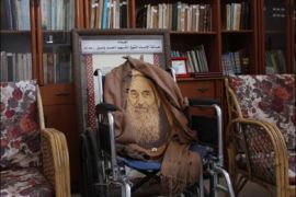 كرسي الشيخ ياسين موشح بصورة للشيخ وغطاء رأسه الذي كان يرتديه لدى استشهاده.