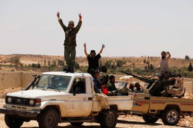 Rebel fighters gesture after pushing back forces loyal to Muammar Gaddafi, on the outskirts of the western town of Riyayna, June 15, 2011.