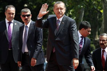 Turkey's Prime Minister Tayyip Erdogan, flanked by guards and officials, waves as he arrives at the first meeting of his new cabinet in Ankara July 7, 2011. Erdogan, whose AK Party won an unprecedented third term in office in an election last month, unveiled