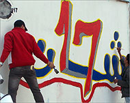 متطوعون يكتبون شعارات الثورة بمدينة شحات (الجزيرة نت)