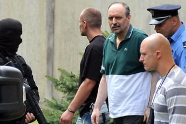 f_Serbian police secures the area while Croatian Serb leader Goran Hadzic (2nd L) is taken to see his ailing mother on July 22, 2011 in Novi Sad ahead of his expected transfer from