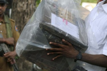f_A Sri Lankan election official is watched by a policeman as he carries a ballot box to be transferred to a main counting centre in the northern town of Jaffna on July 23, 2011