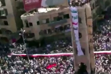 f_An image grab from a video uploaded on You Tube shows anti-government demonstrators carrying a huge Syrian flag during an anti-government demonstration in the center of Hama
