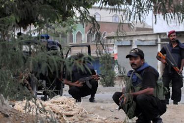 Pakistani policemen take positions while on alert in a tense area of Karachi on July 5, 2011.