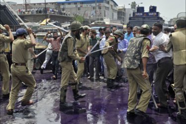 Indian policemen use batons as they attempt to stop Kashmiri government employees during a protest in Srinagar on July 18, 2011.