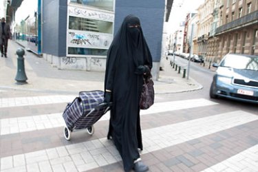 epa02133522 A muslim woman dressed in niqab (veil which covers the body and leaves only a small strip for the eyes) walks through the streets of Brussels, Belgium, 27 April 2010.