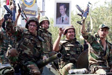 Syrian soldiers raise their weapons while holding a picture of Syrian President Bashar al-Assad as they leave the eastern city of Deir Zor following a 10-day military operation on August 16, 2011.