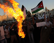 المتظاهرون يحرقون العلم الإسرائيلي في مظاهرة سابقة أمام السفارة الإسرائيلية (الجزيرة-أرشيف)