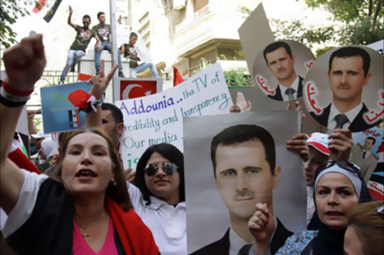 Syrian citizens and journalists holds portraits of President Bashar al-Assad as they protest outside the EU offices in Damascus on September 29, 2011 against new EU sanctions imposed on the pro-government Addounia television channel and five other companies.